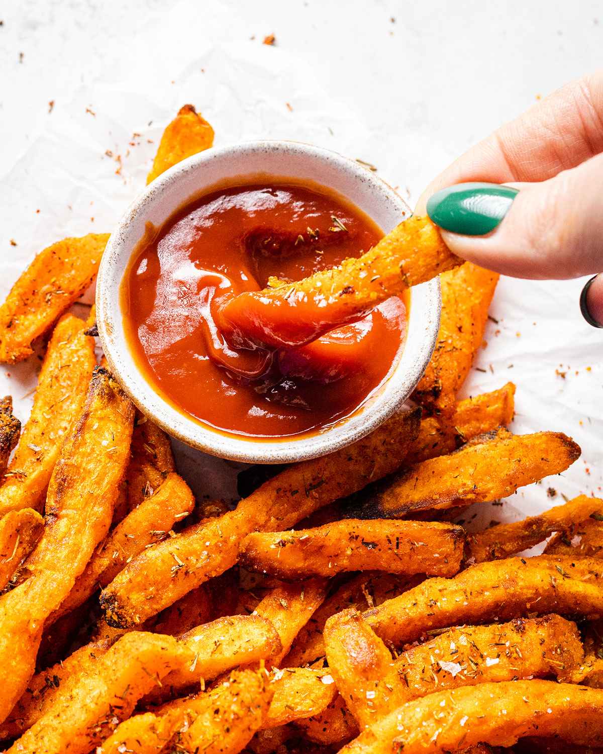 A sweet potato fry dipped into ketchup.