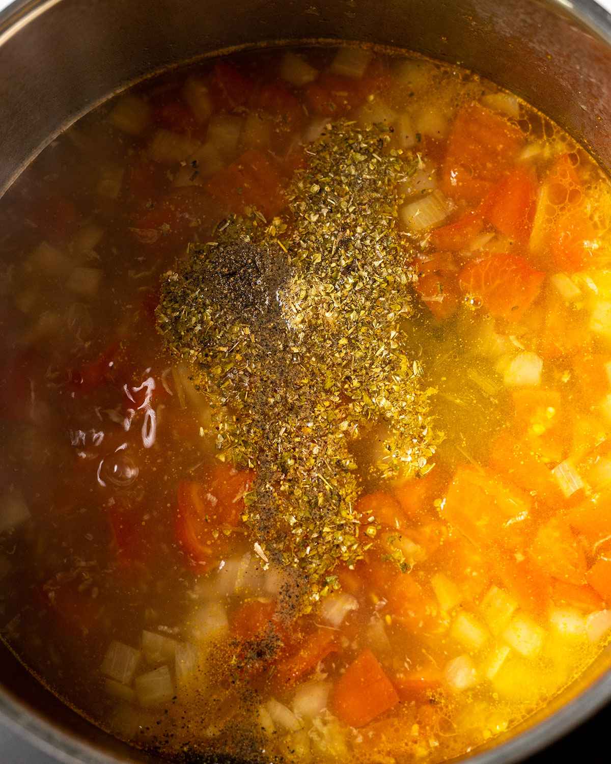 close up of oregano on top of caldo de queso in a saucepan