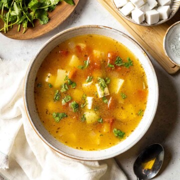 cheese and potato soup on a dinner table topped with black pepper and fresh cilantro