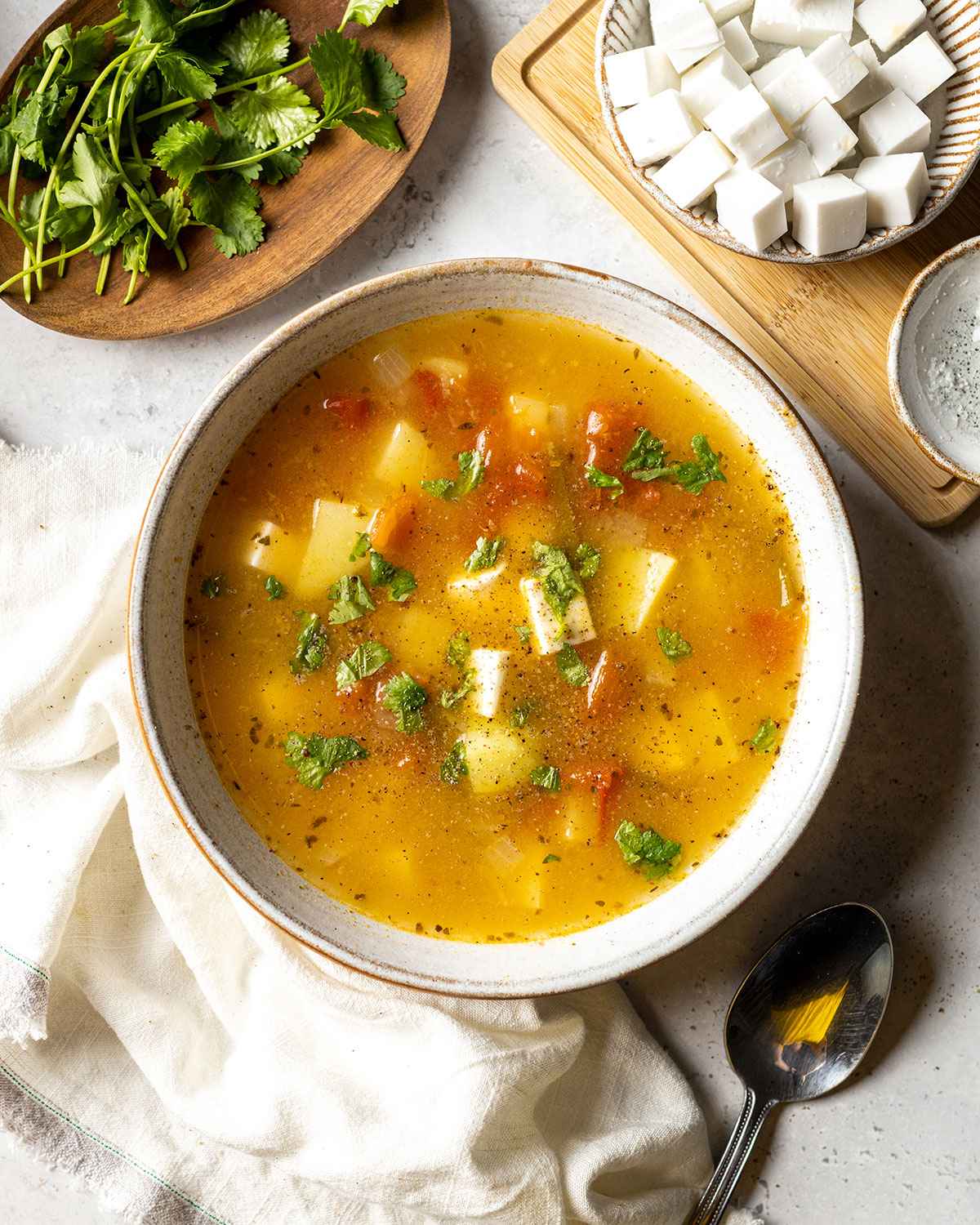 cheese and potato soup on a dinner table topped with black pepper and fresh cilantro