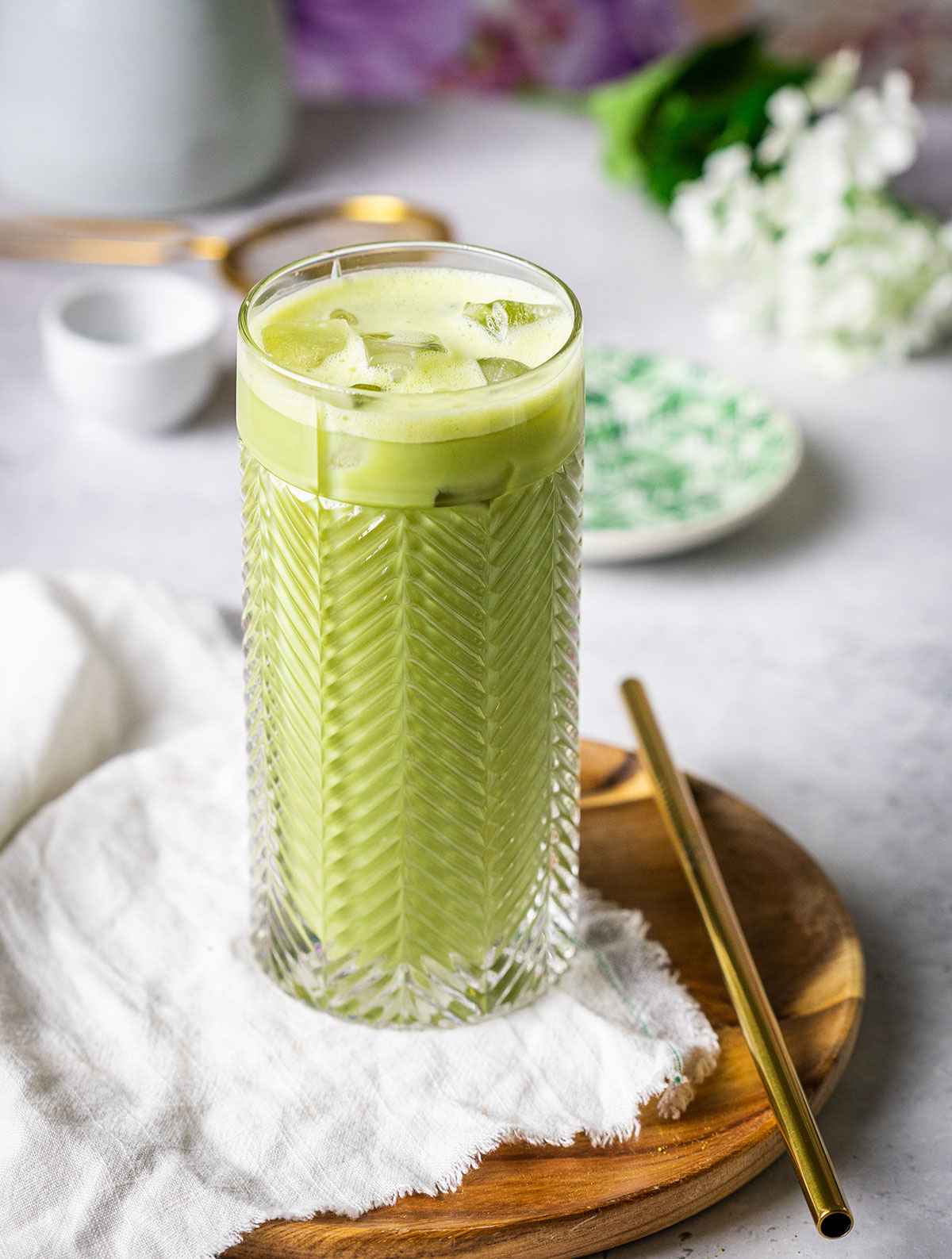 iced matcha latte in a tall glass on a wooden serving tray