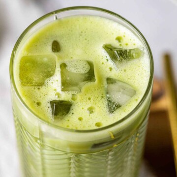 a tall glass filed with iced matcha latte, closely showing the top of the drink and the ice cubes in the glass