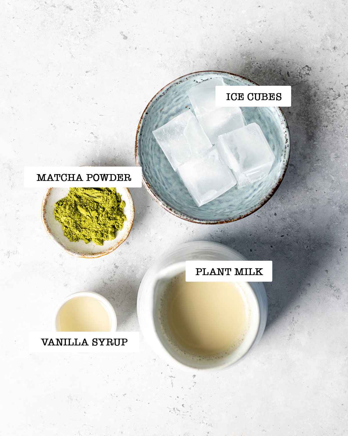 ingredients for iced matcha latte starbucks style on a white marble table