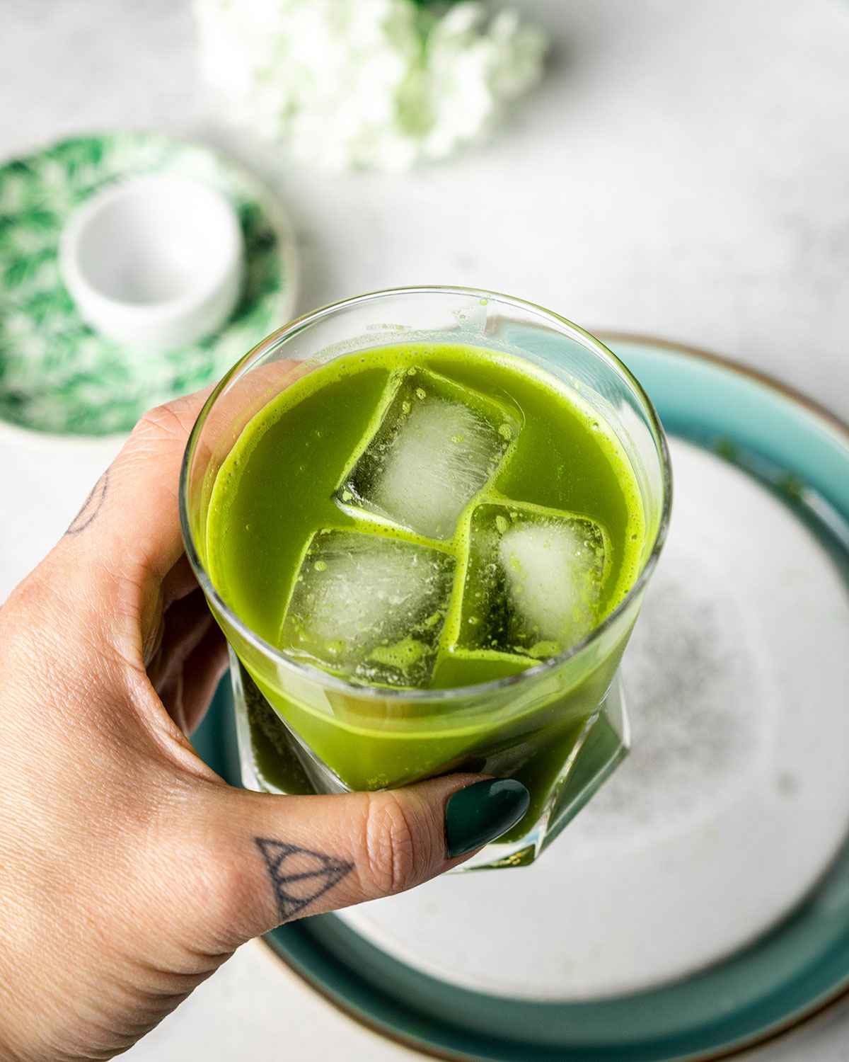 a hand holding a glass of matcha lemonade