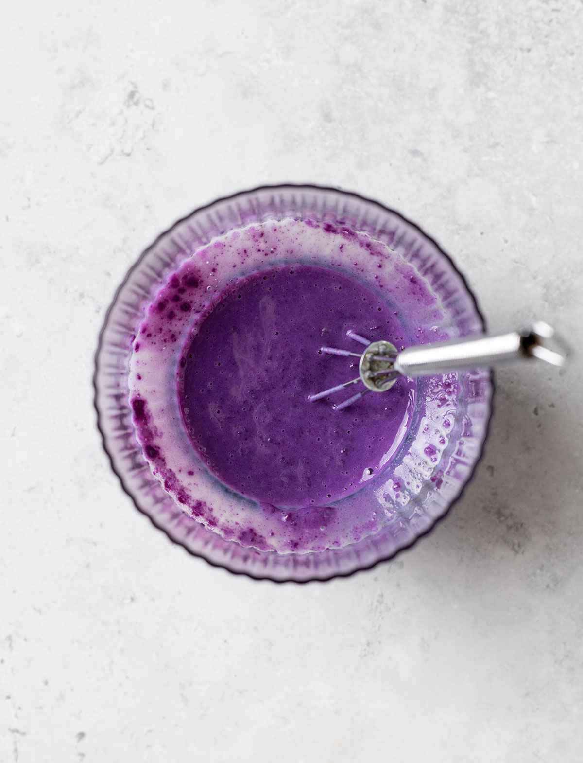 dissolved purple yam powder in water with a whisk in a glass