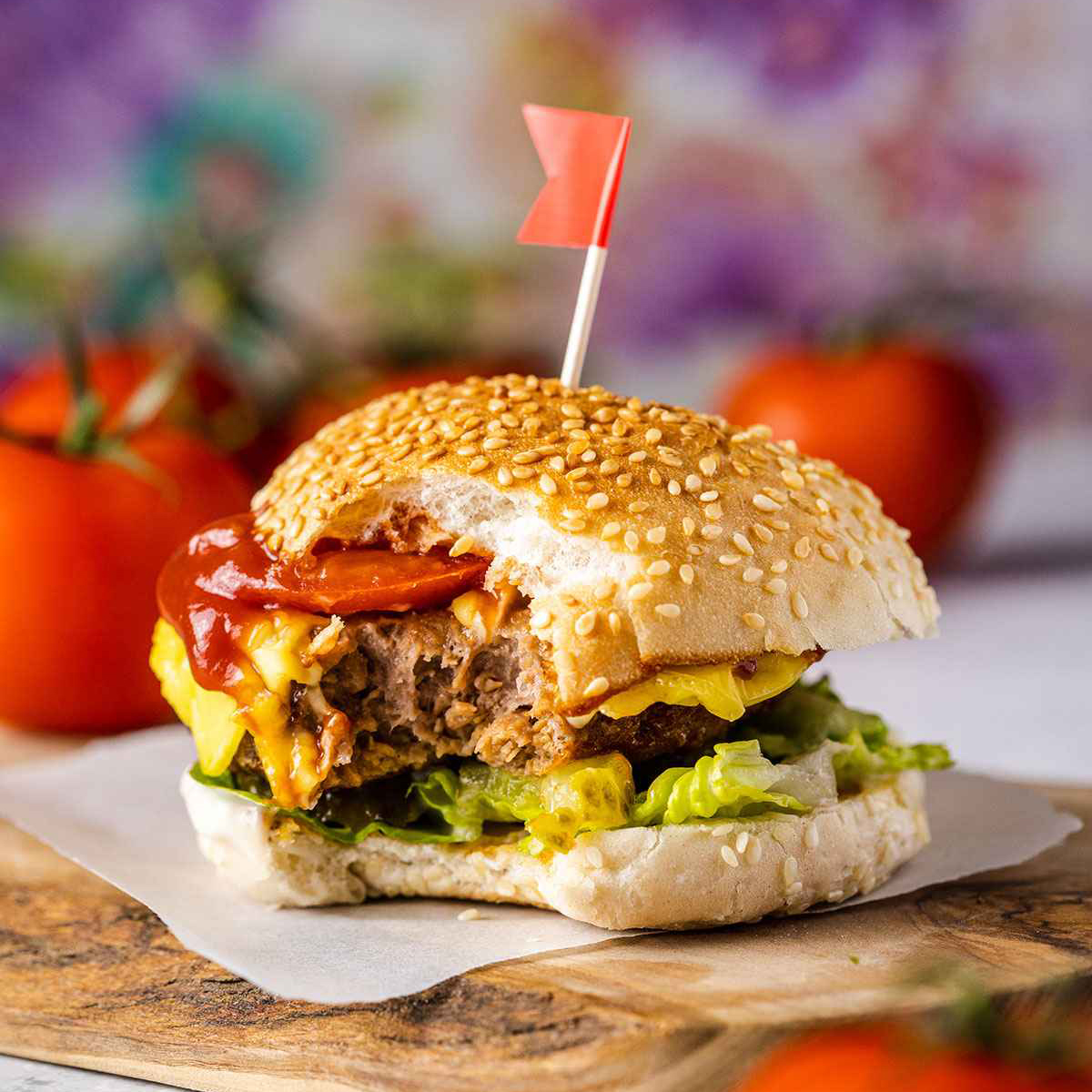 an air fryer frozen burger sitting on a woodden serving board with a bite taken out of it