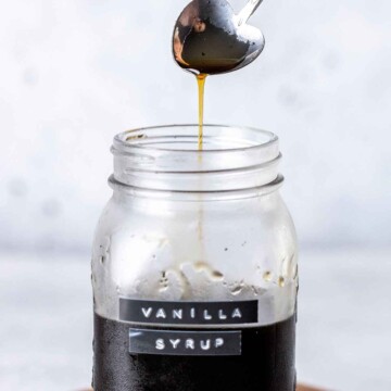 a spoon drizzling vanilla syrup into a glass jar