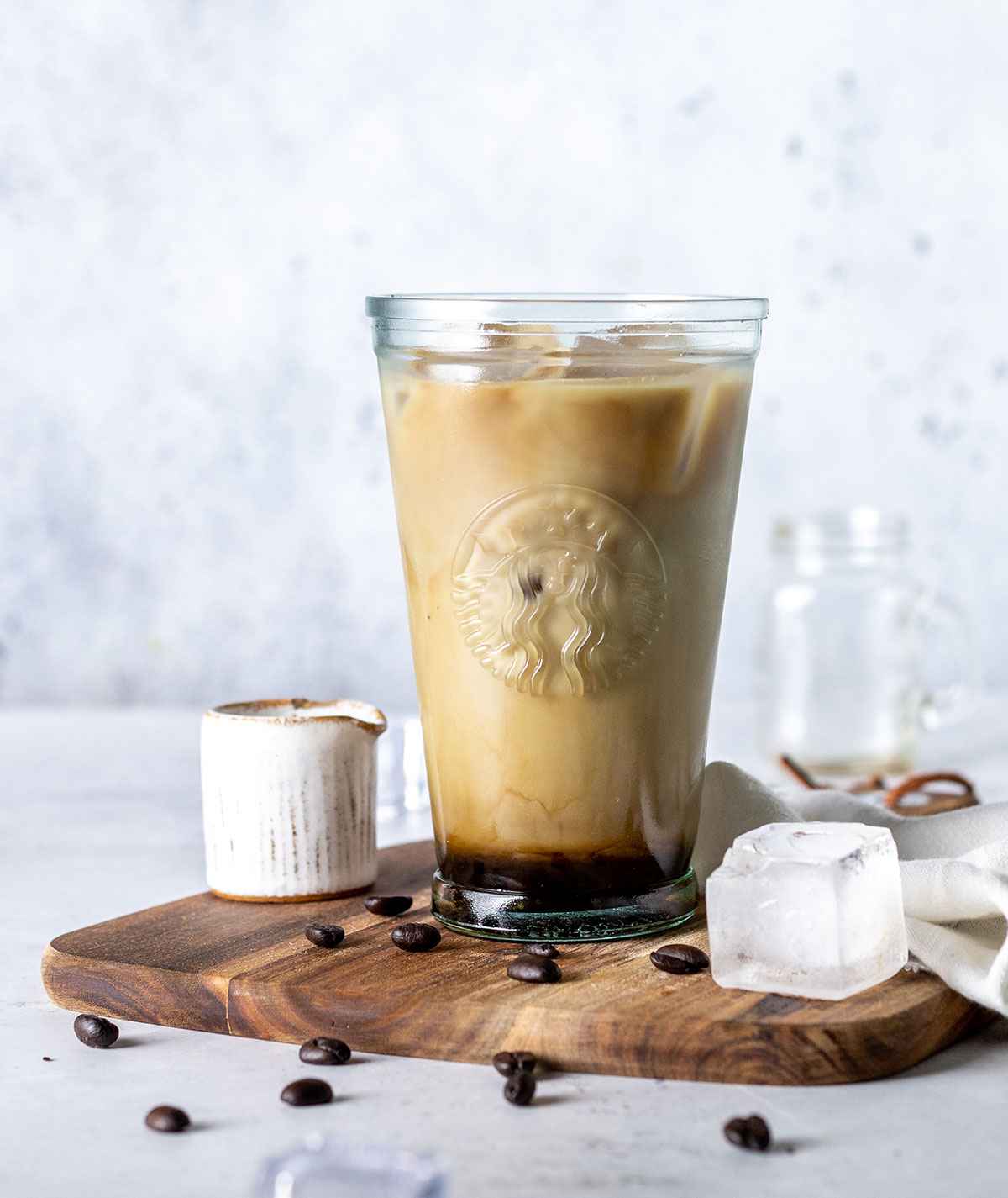 A glass filled with iced vanilla latte on a wooden board