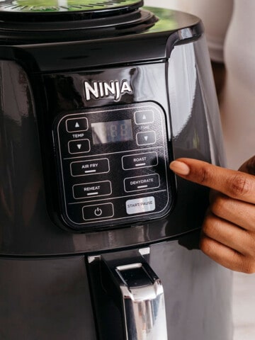 ninja air fryer with a hand tapping on the display