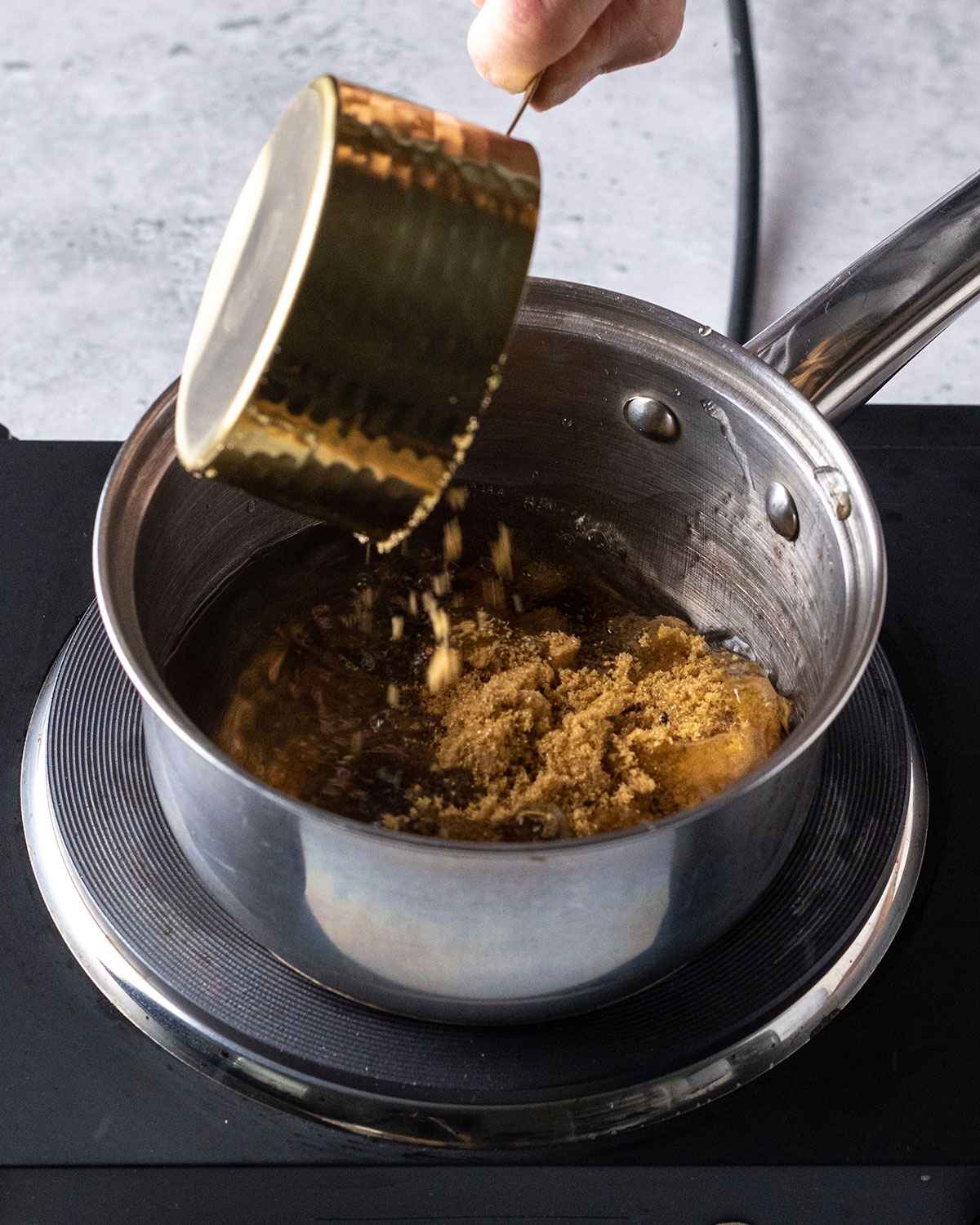 adding brown sugar to a saucepan with water