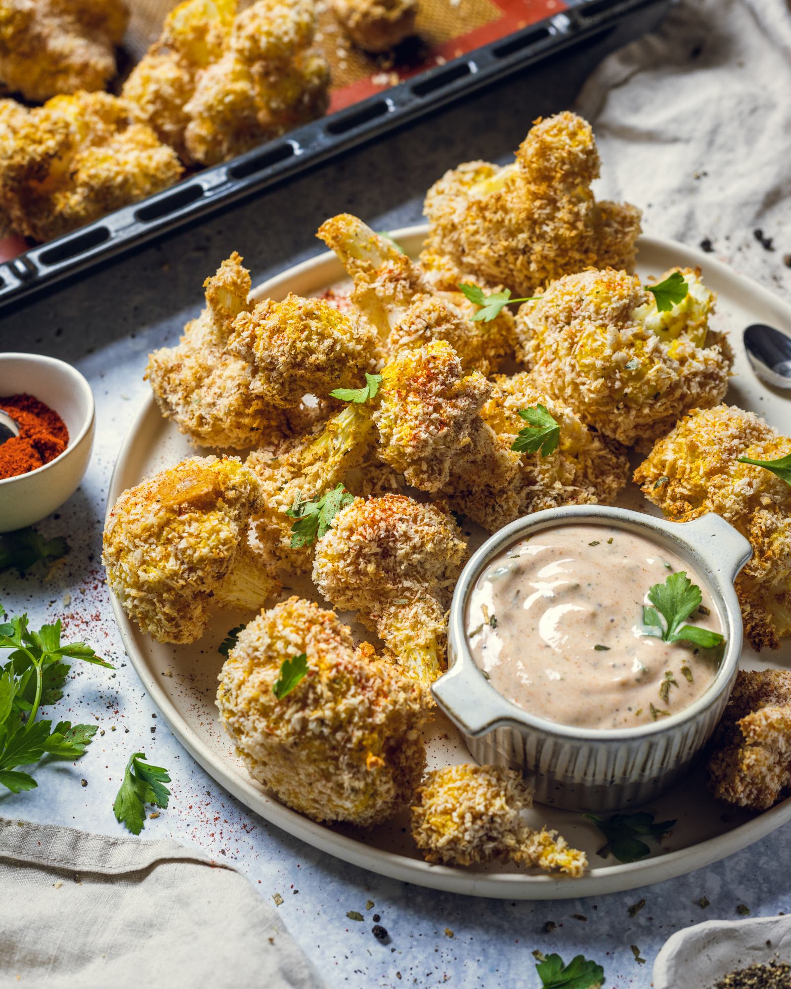 Crispy vegan cauliflower wings are sitting on a serving platter next to a dip.