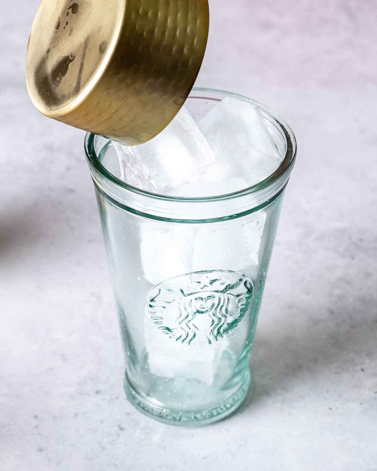 pouring ice cubes into a tall glass