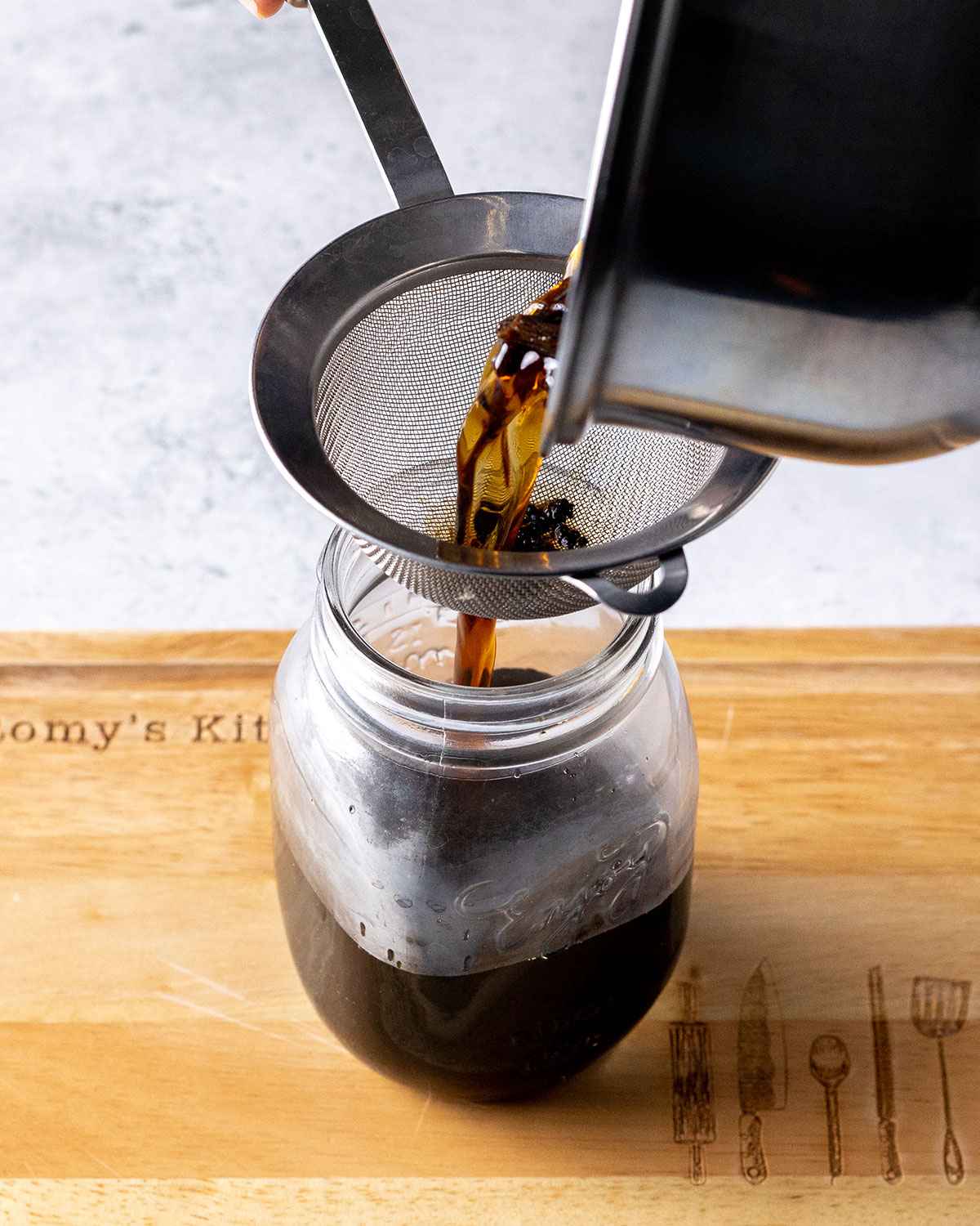 pouring vanilla syrup through a sieve