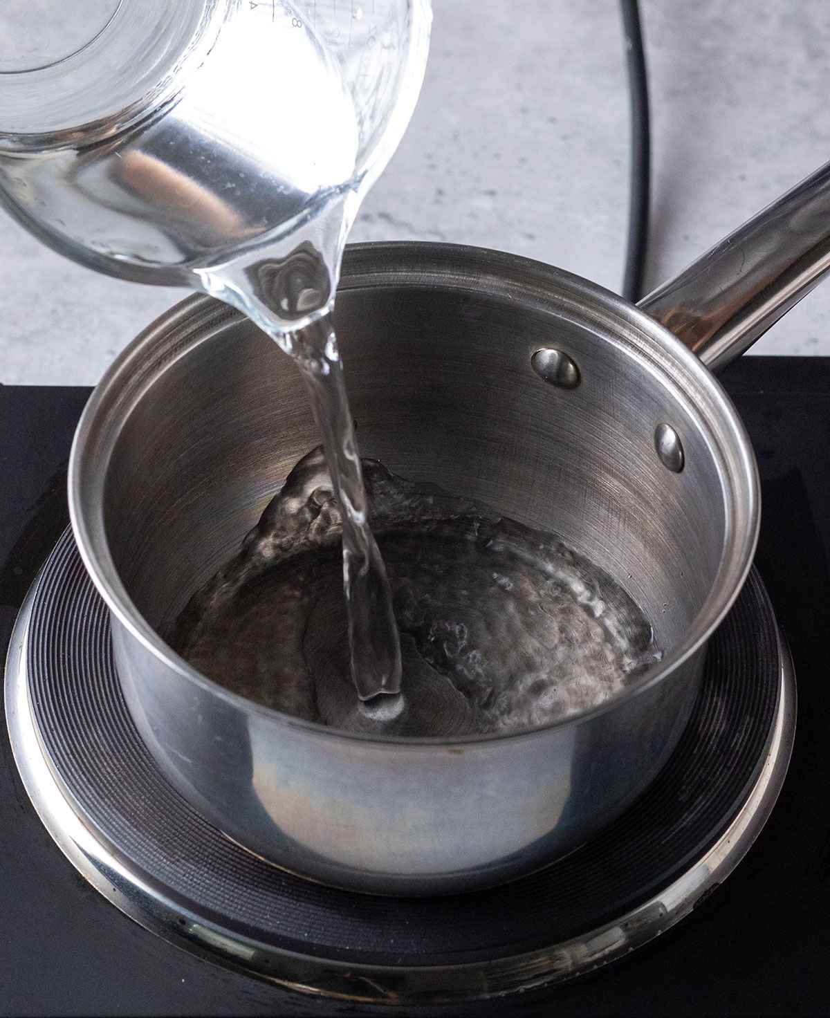 pouring water into a saucepan