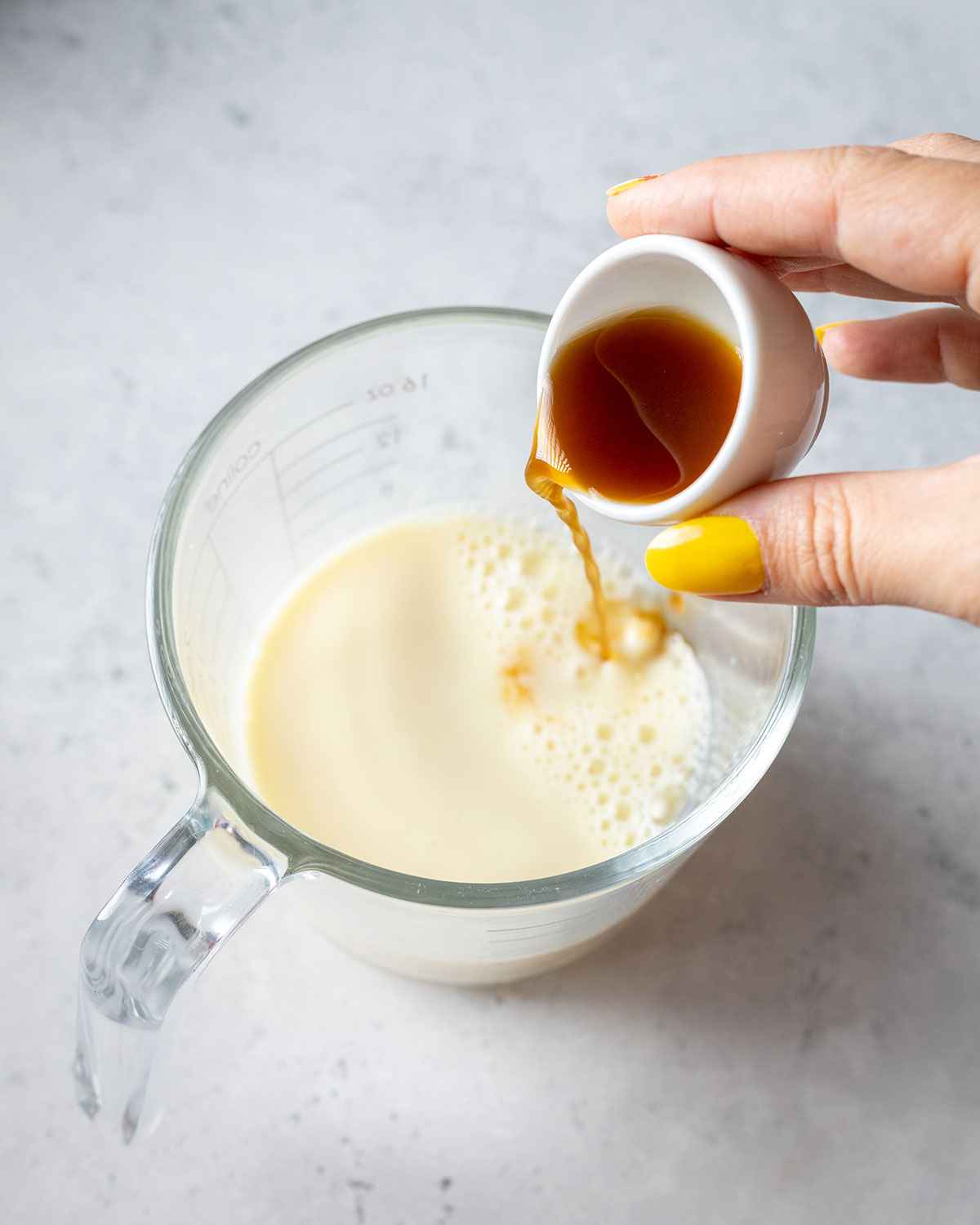 vanilla extract being added to a jug of milk