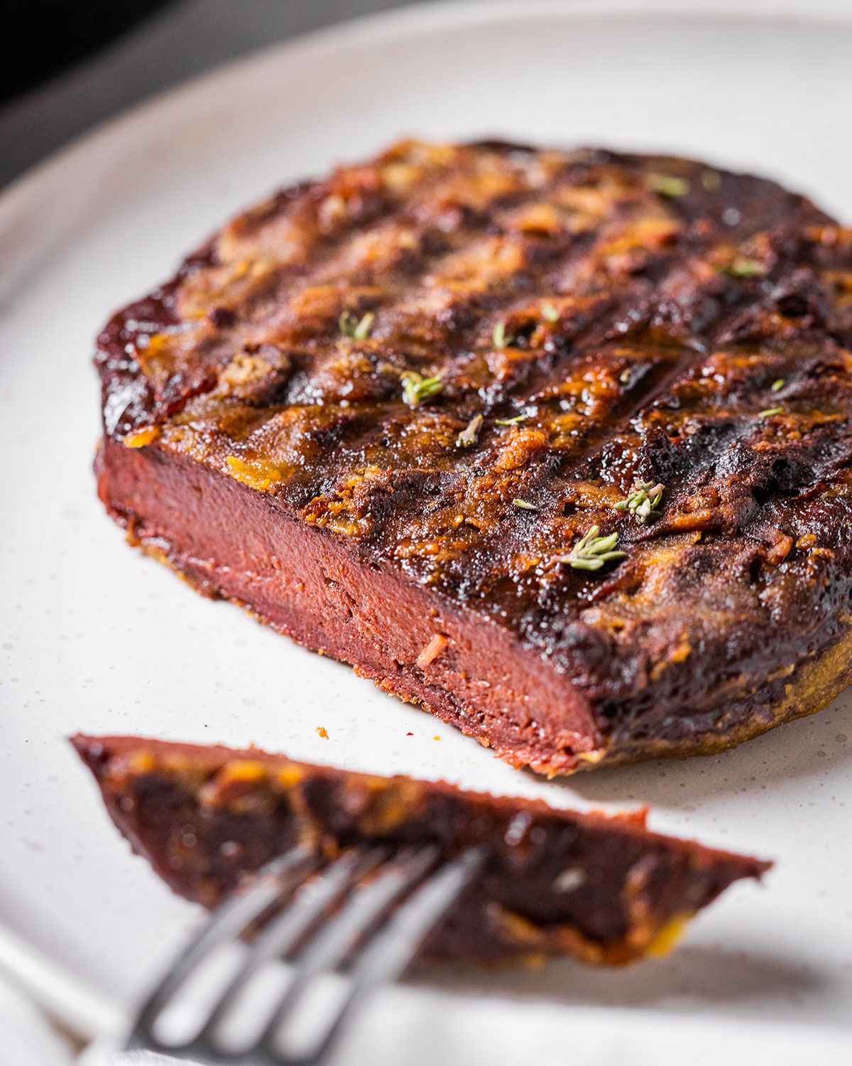 vegan steak on a plate with a piece sliced off on a fork