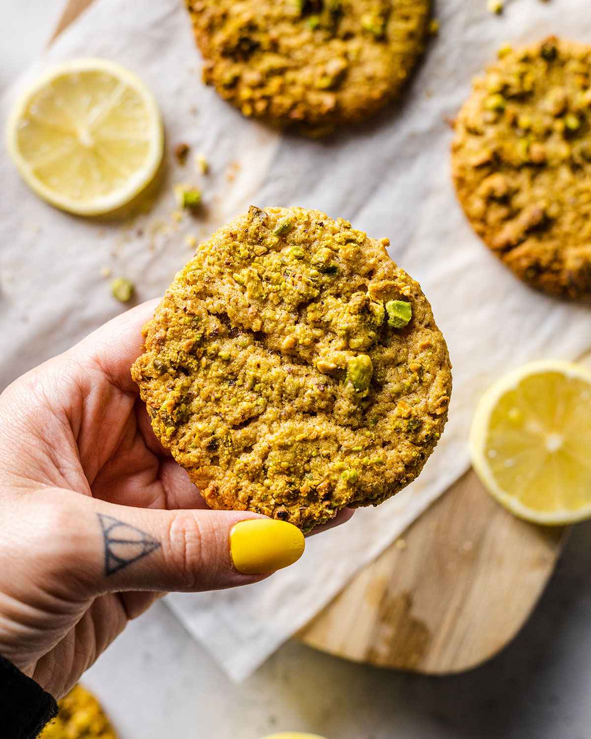 A hand holding up a pistachio cookie.