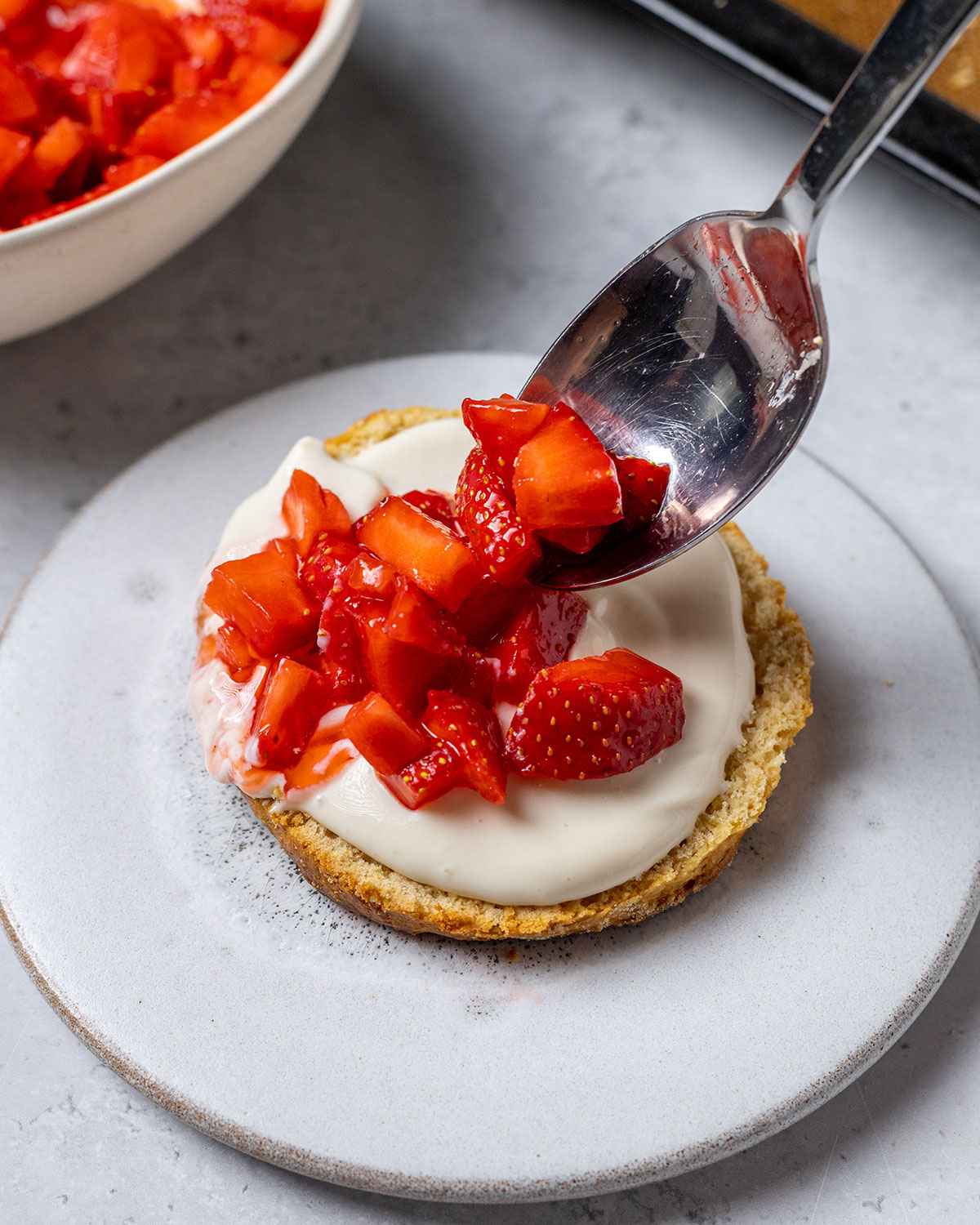 spooning chopped strawberries onto the coconut cream on shortcake