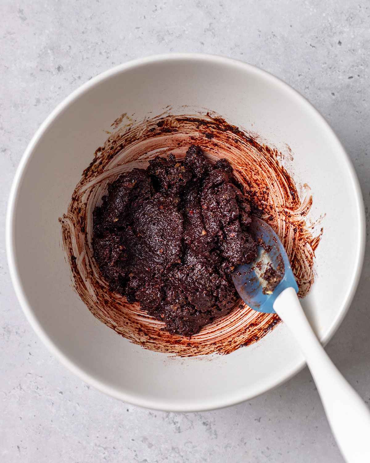 mixed flavor paste with a small spatula in a white bowl