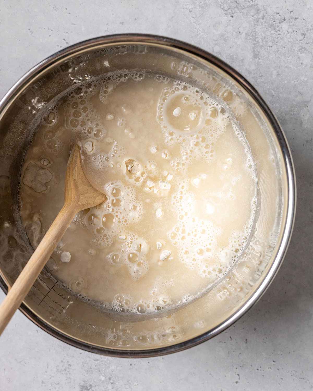 flour and water in a bowl with a wooden spoon before mixing into a dough ball