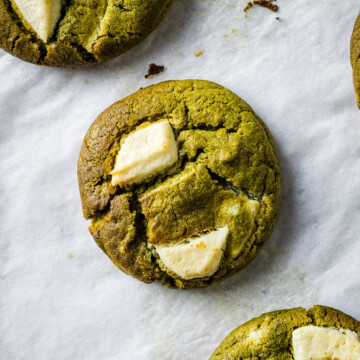 Matcha green tea cookies with white chocolate chips on a white baking parchment