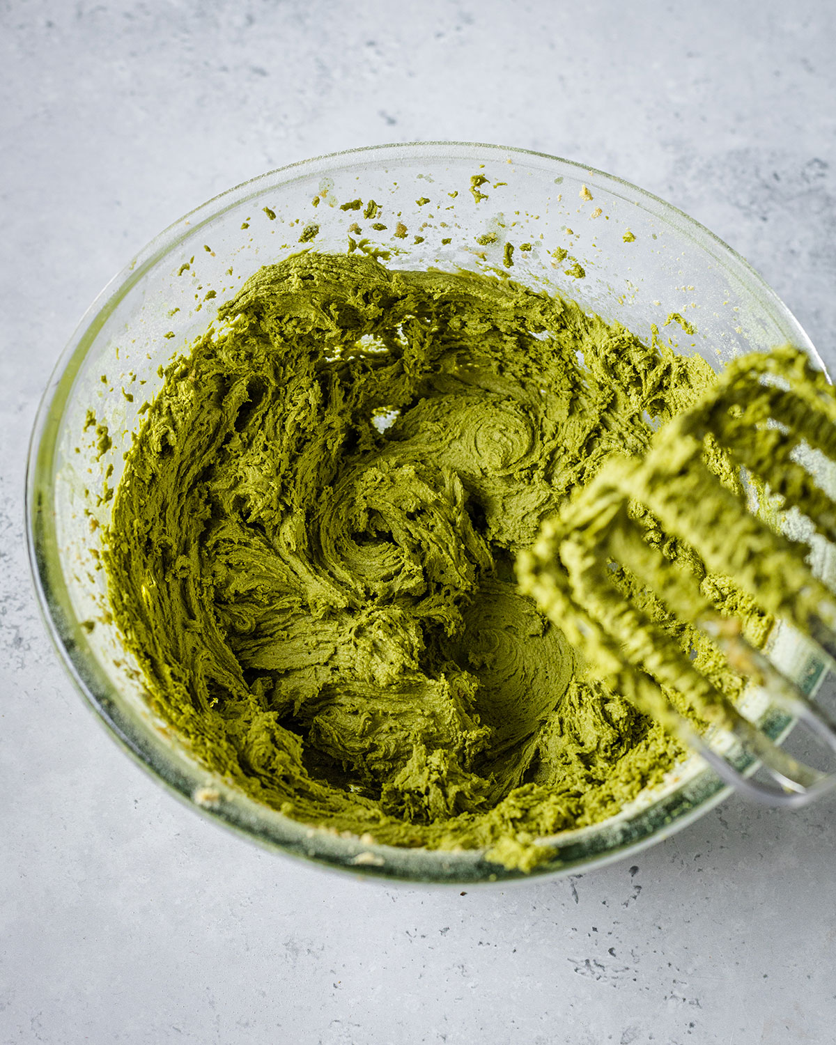 Matcha cookie dough in a glass bowl on a marble surface