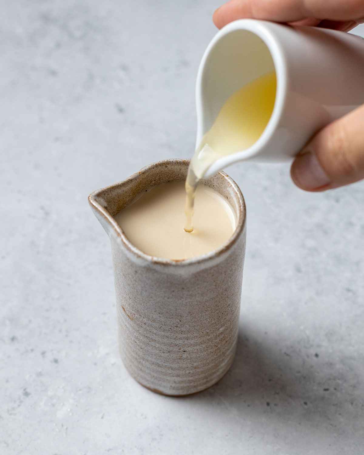 pouring apple cider vinegar into a jug with plant milk