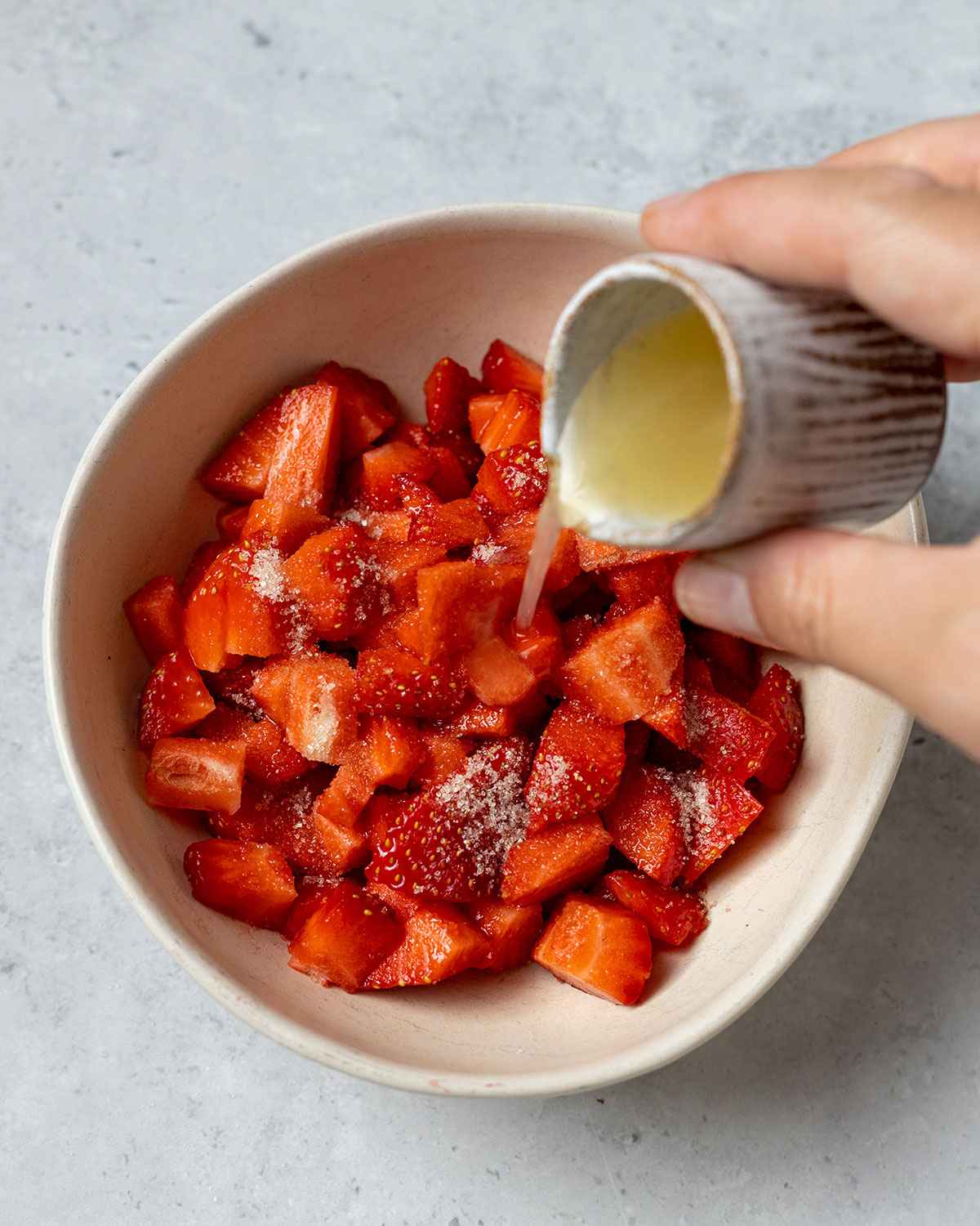 pouring fresh lemon juice onto chopped strawberries