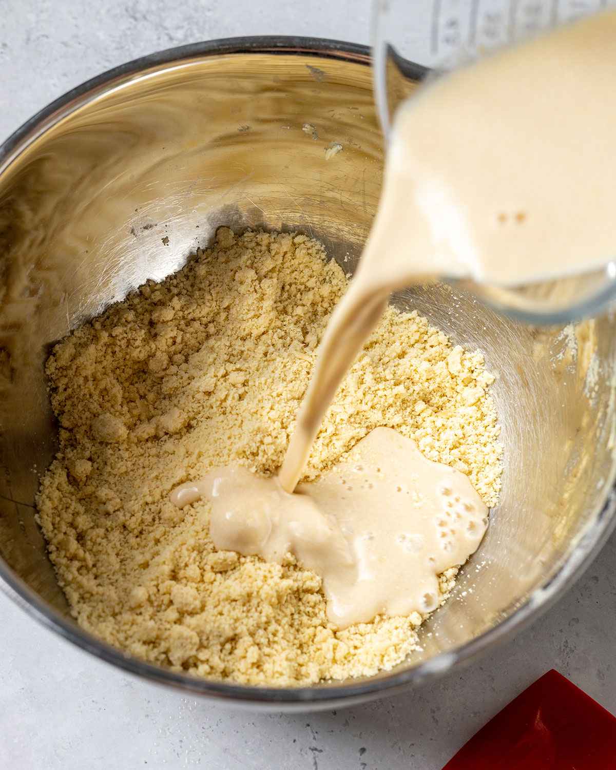 pouring vegan buttermilk into the bowl with the dry ingredients