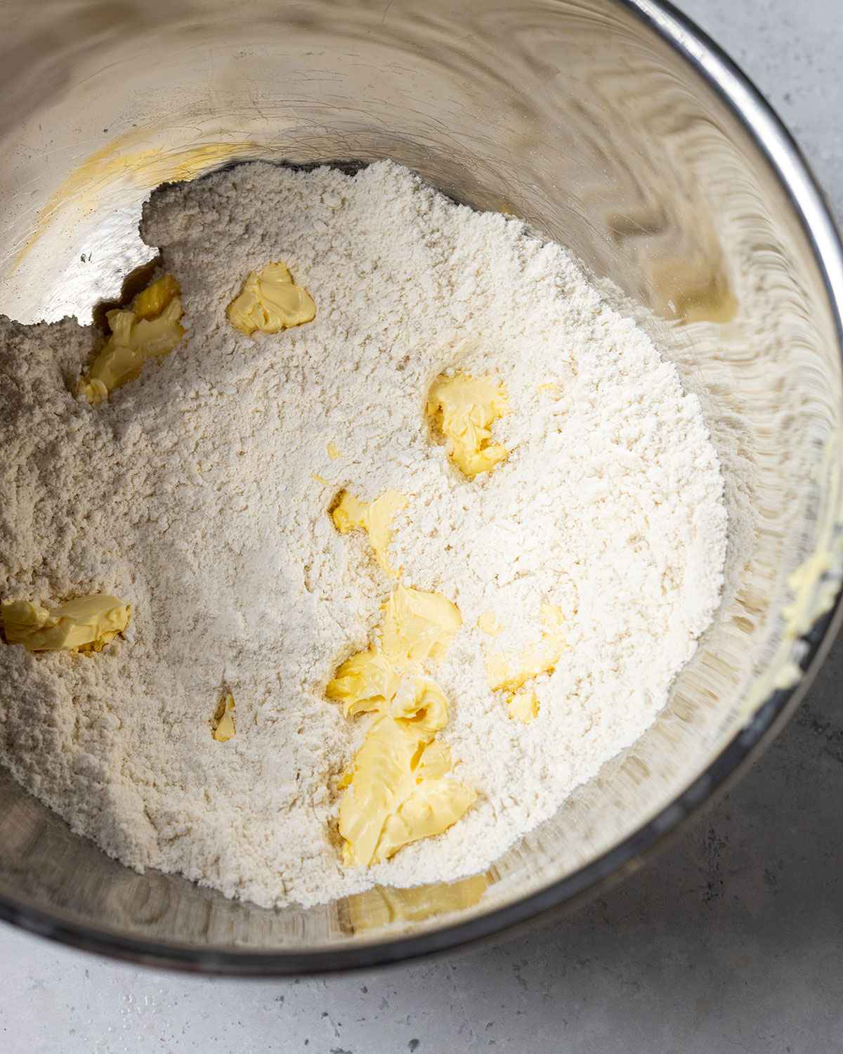 flour and butter in a mixing bowl, the butter is in small chunks