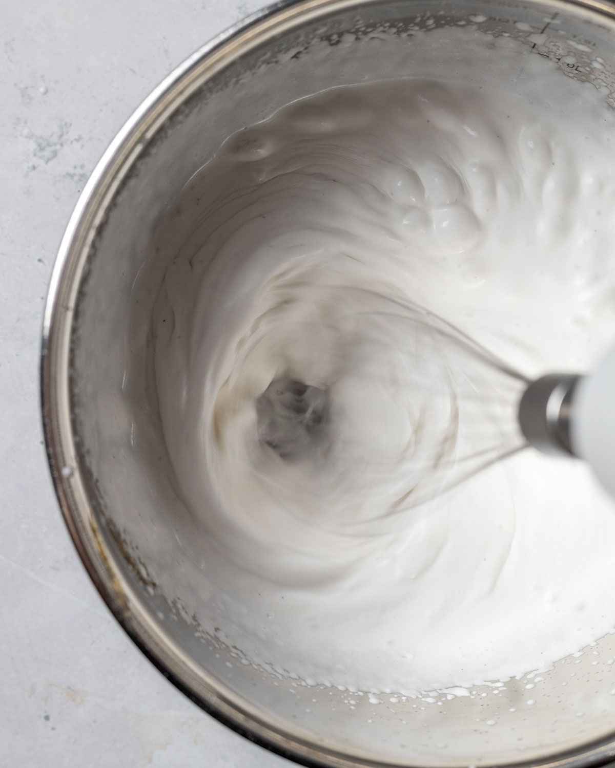 whipping coconut cream in a bowl with an electric hand whisk