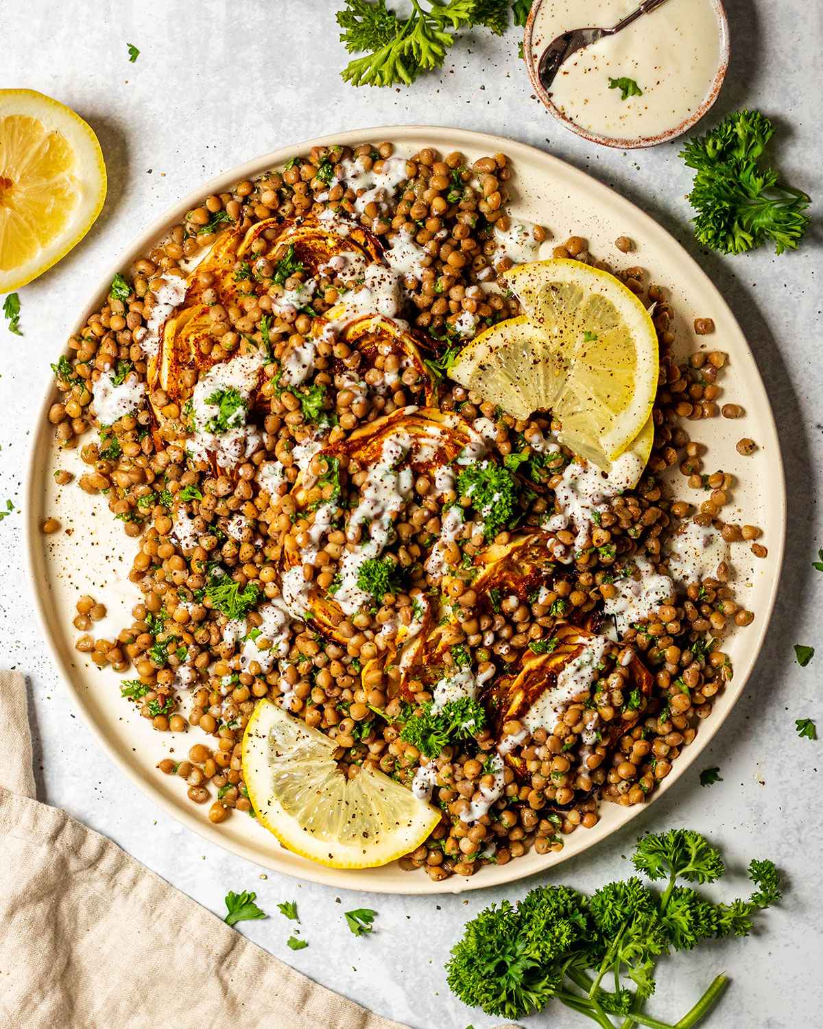 A serving platter is filled with lentil and cabbage salad on a marble table top.