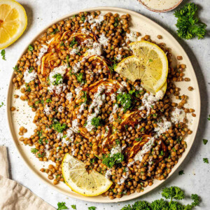 roasted cabbage steaks and lentil salad on a white serving platter on a marble table surrounded by ingredients