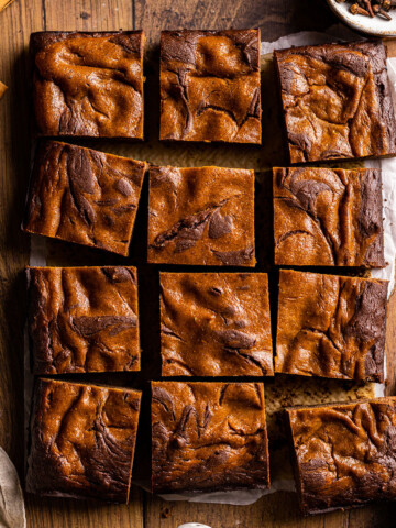 Thumbnail for vegan pumpkin brownies photographed as a flatlay on a wooden table, cut into pieces