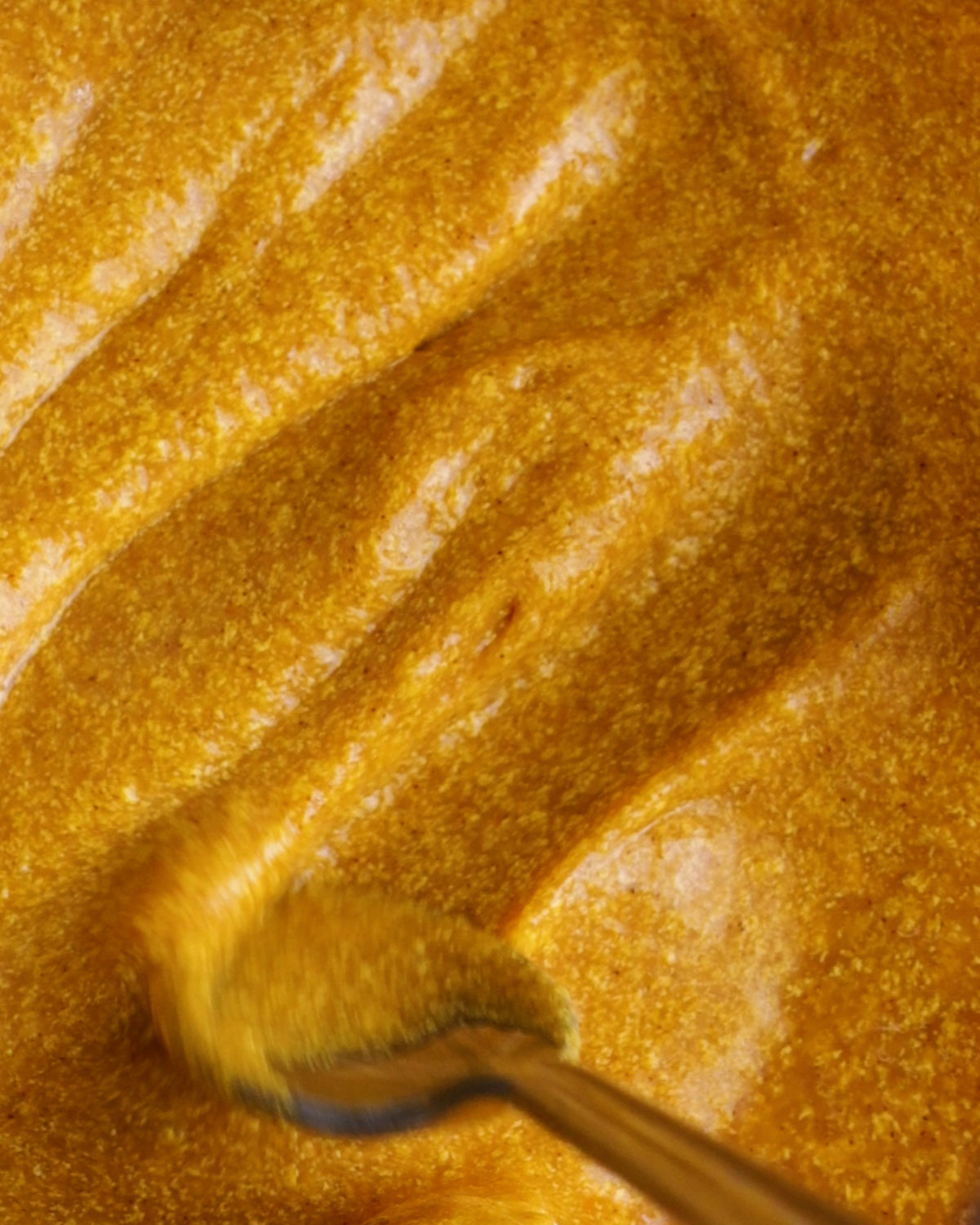 a spoon stirring a smooth pumpkin cheesecake mix