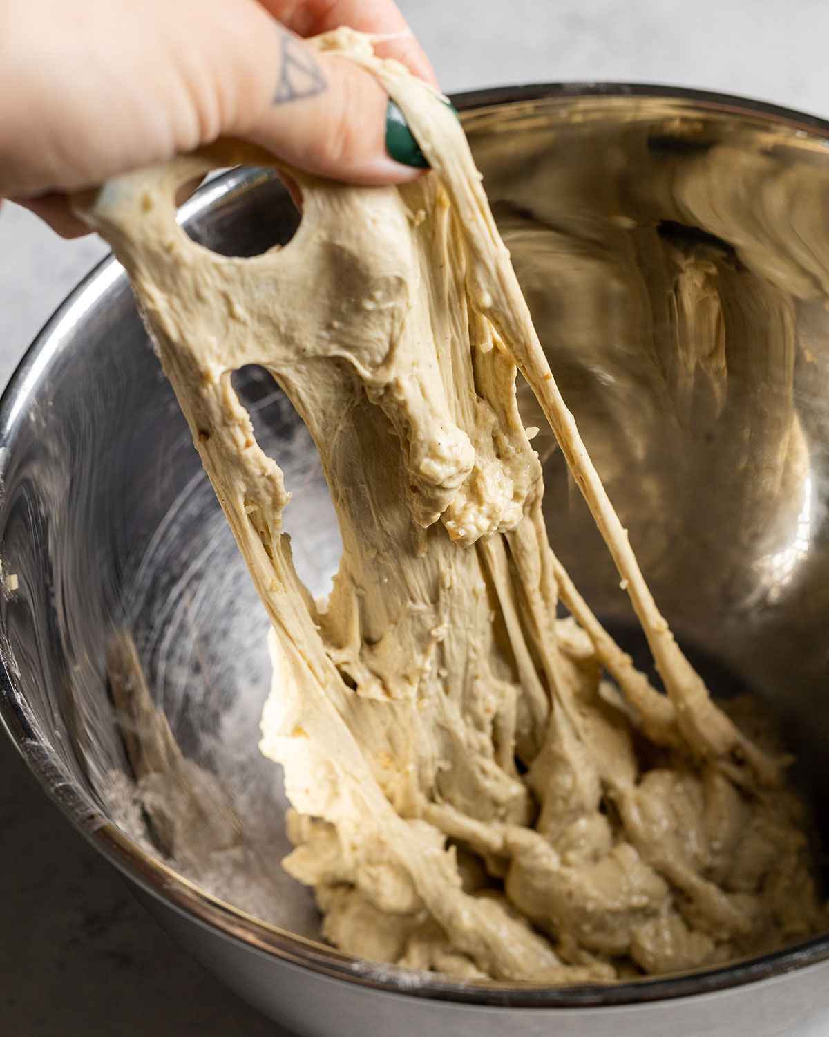 hand pulling seitan dough in a bowl