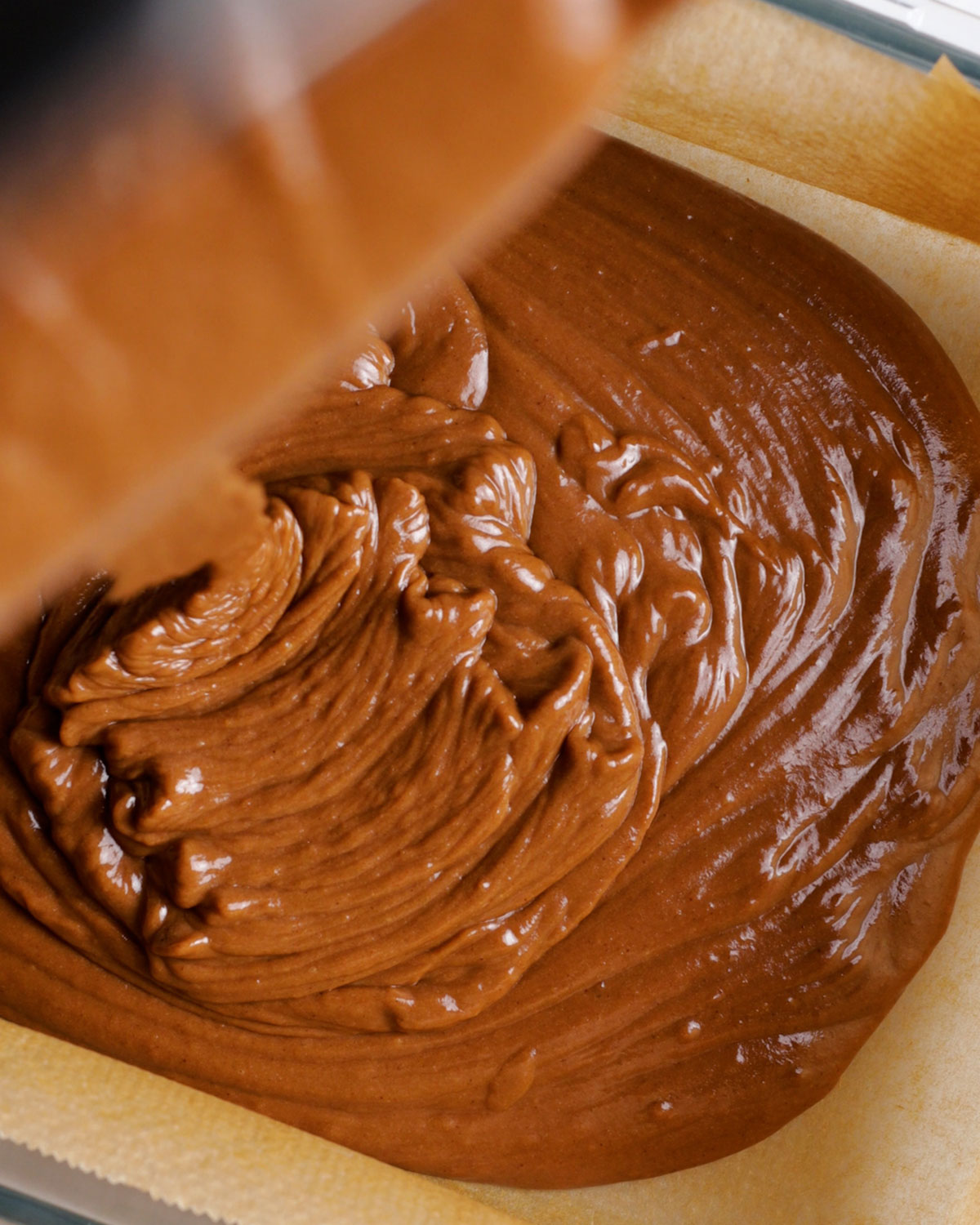 pouring chocolate brownie mix into an oven dish