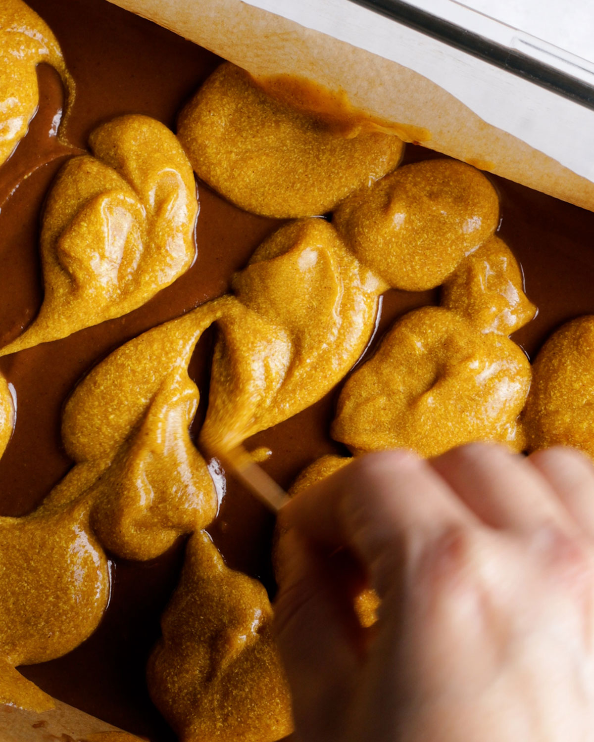 swirling pumpkin cheesecake onto vegan brownies