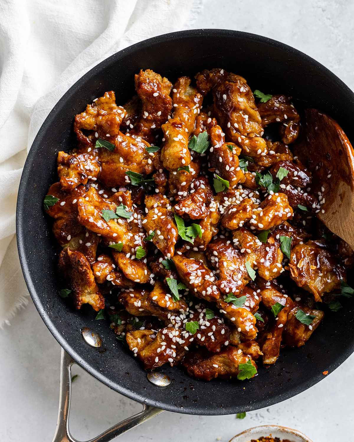 vegan buffalo chicken made from seitan in a skillet with sesame seeds and herbs on top 3