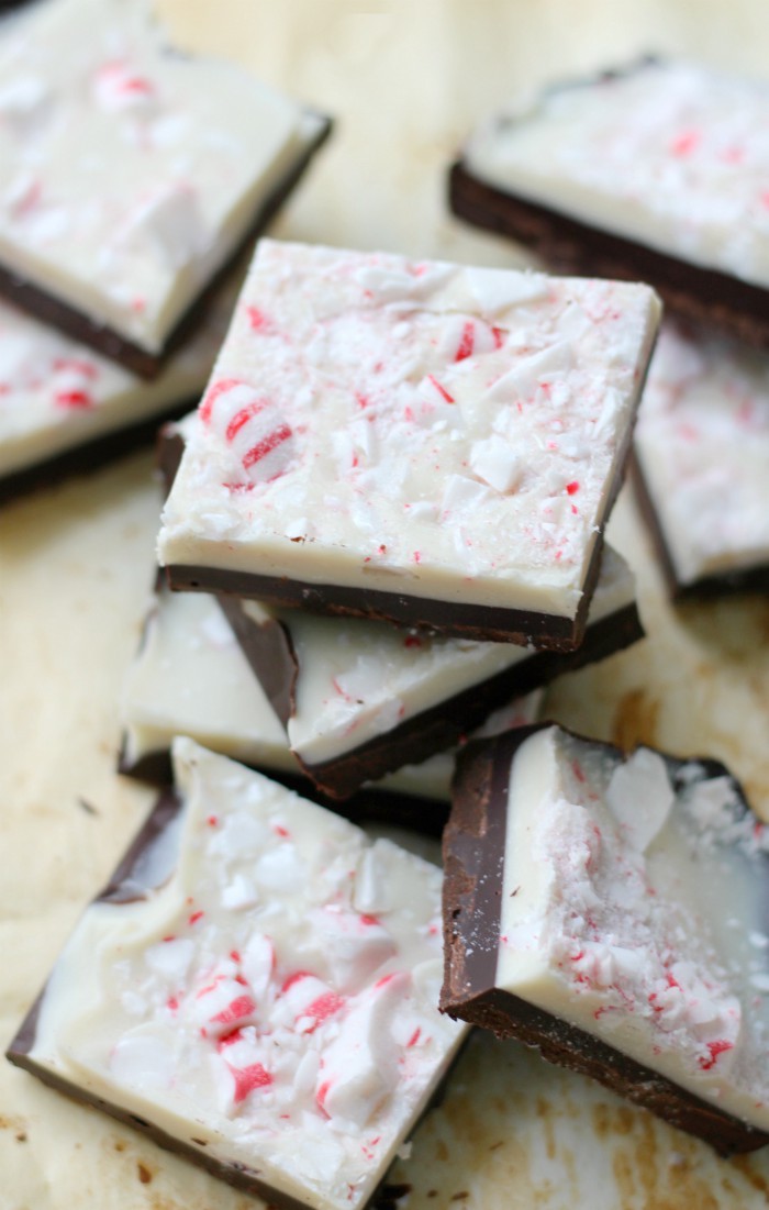 square vegan peppermint bark slices with 2 layers of vegan chocolate and topped with vegan candy canes, on a pile