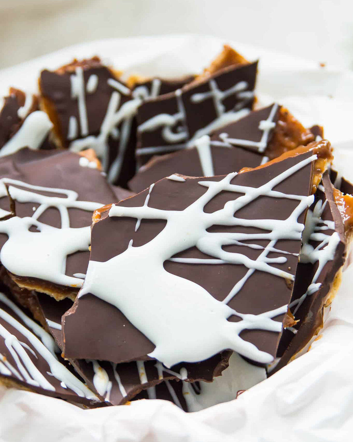 Vegan christmas crack in a white bowl, dark chocolate with a white chocolate drizzle