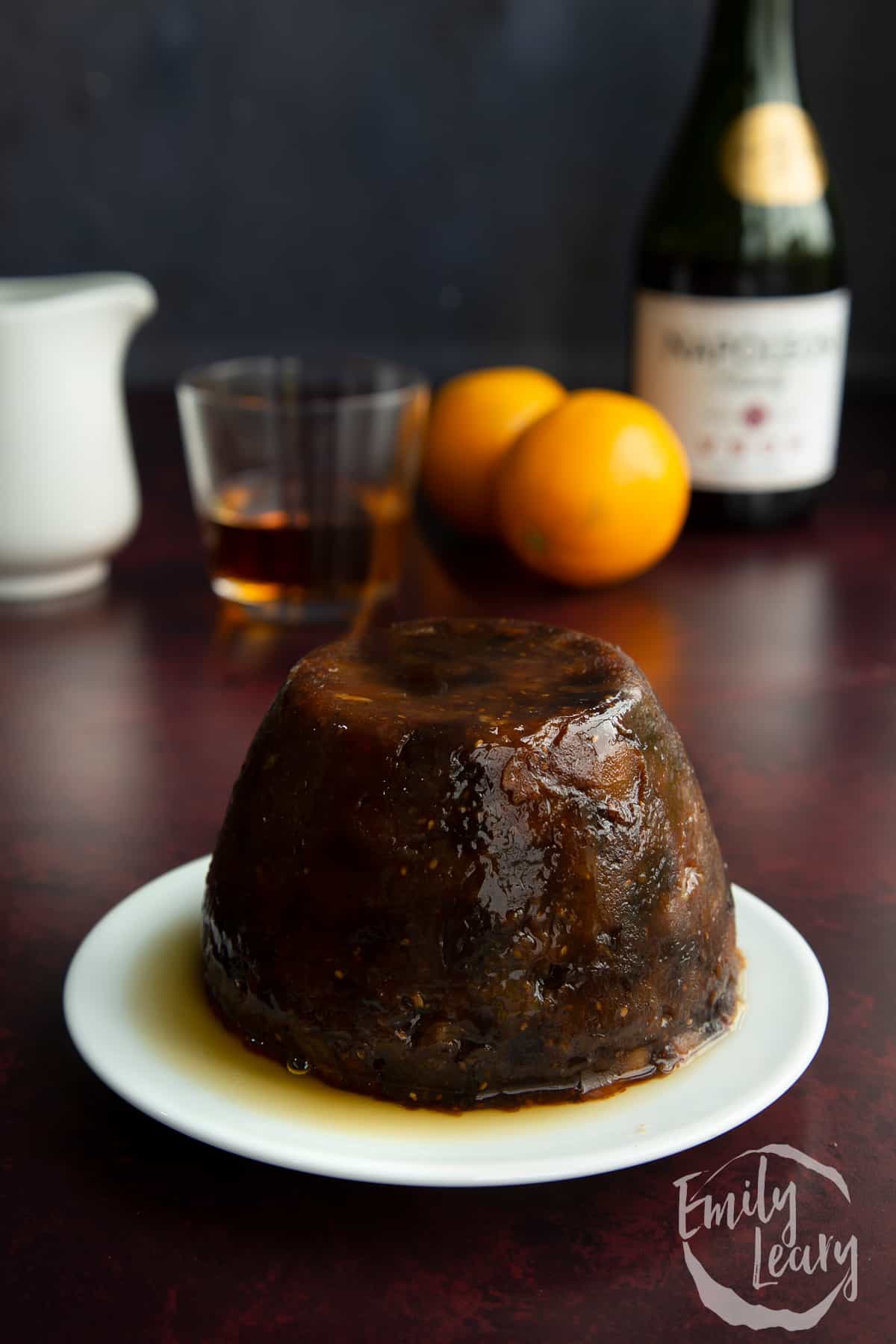 vegan christmas pudding on a white plate with ingredients in the background
