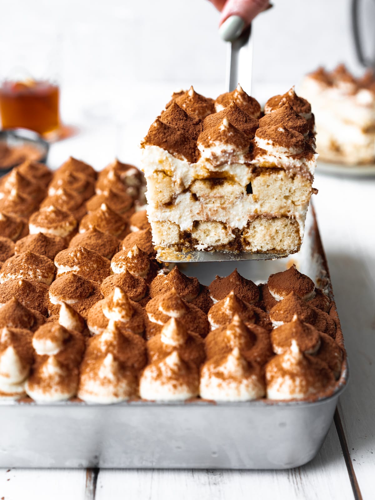 vegan tiramisu in a large tray with a spatula lifting out a portion