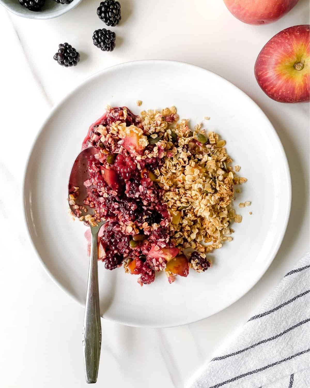 vegan blackberry crisp in a white bowl with a spoon