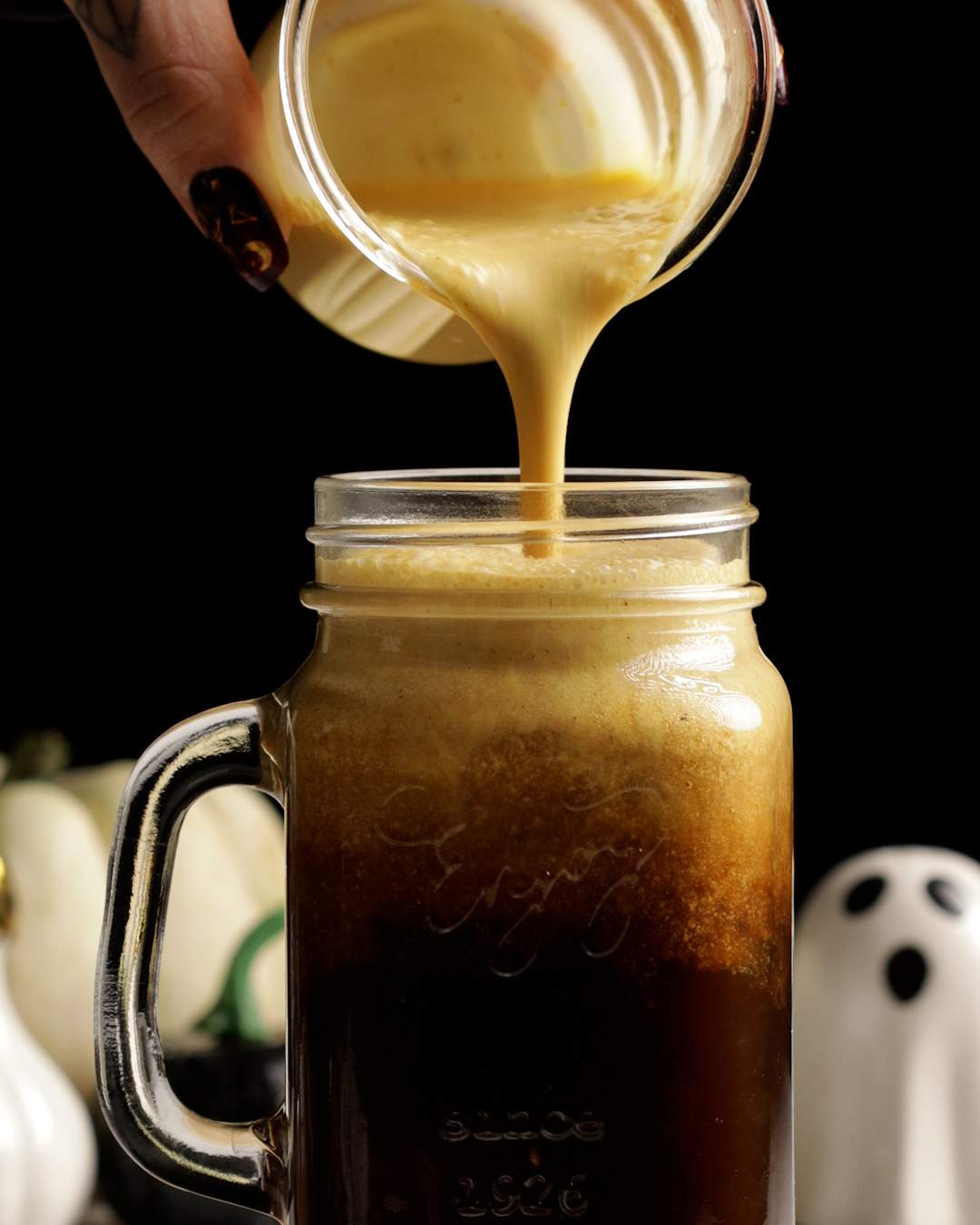 pouring pumpkin cream cold foam onto cold brew coffee 2