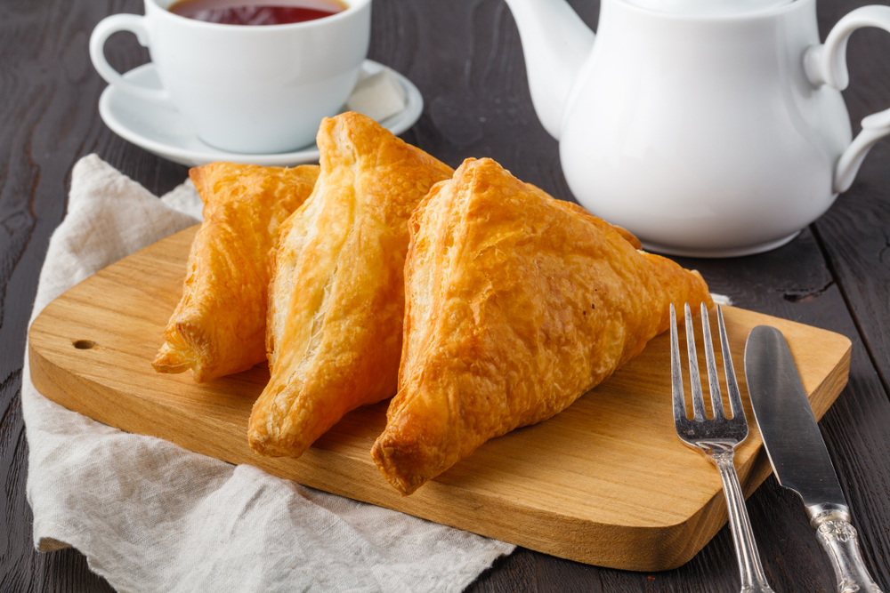 3 triangular vegan pastries on a wooden board