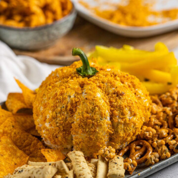 Pumpkin Cheese Ball on a serving platter with snacks and crisps around