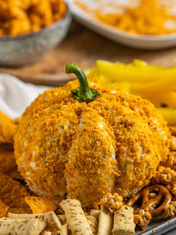 Pumpkin Cheese Ball on a serving platter with snacks and crisps around