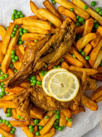 vegan banana blossom dish on a serving of french fries with peas and lemon slices, as seen from above