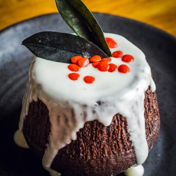 vegan chocolate fondant on a dark plate decorated like a Christmas pudding